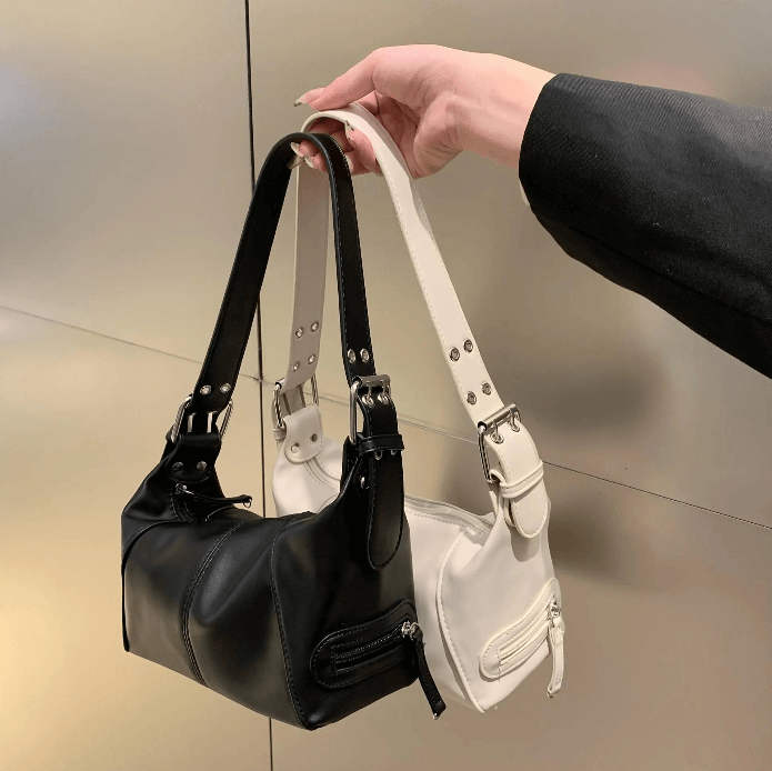 Stylish woman showcasing two fashionable bags, one in a sleek black design and the other in a vibrant color, exuding confidence and elegance.